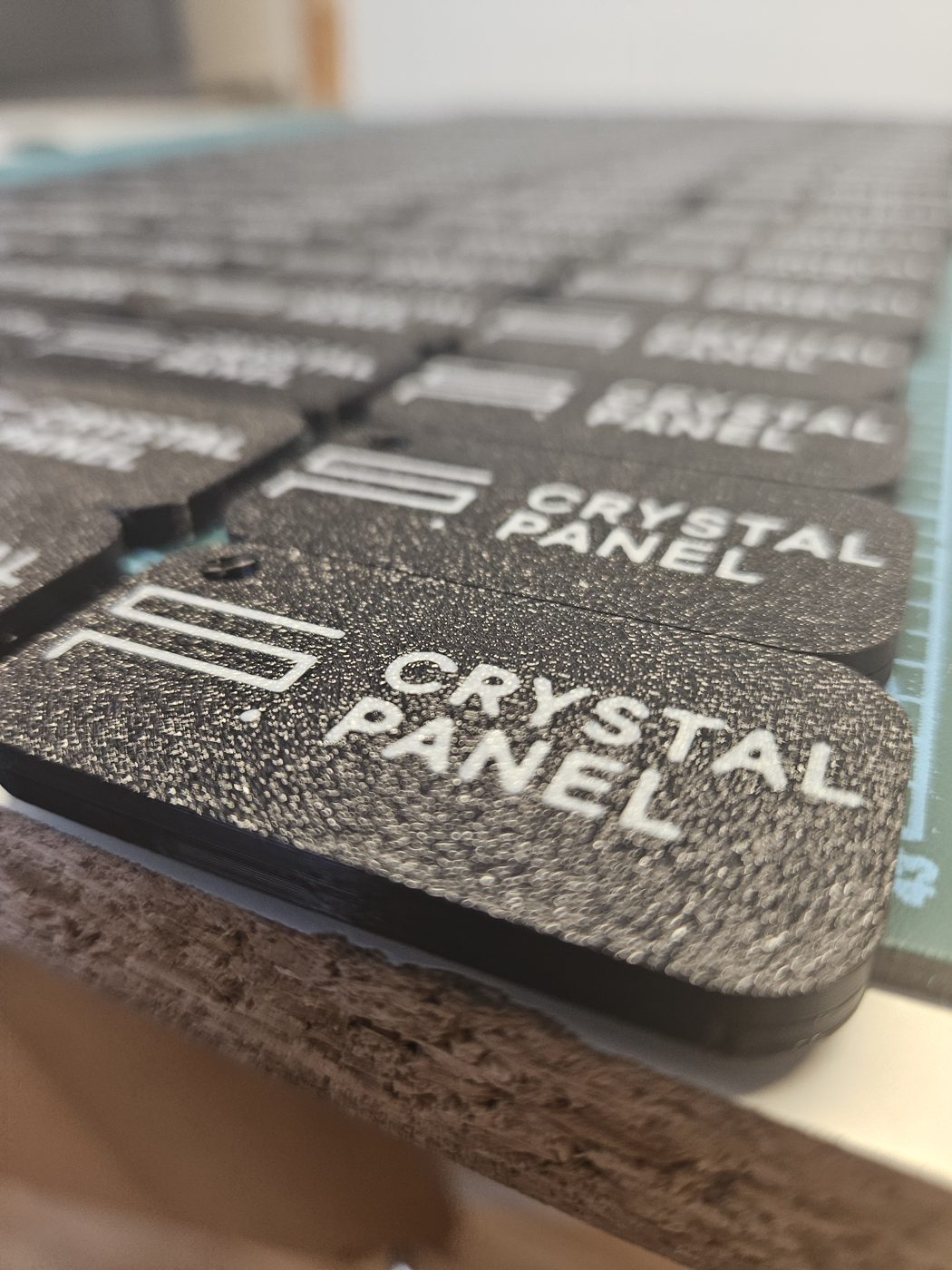Zbliżenie na czarny brelok z białym logo Crystal Panel z druku 3D